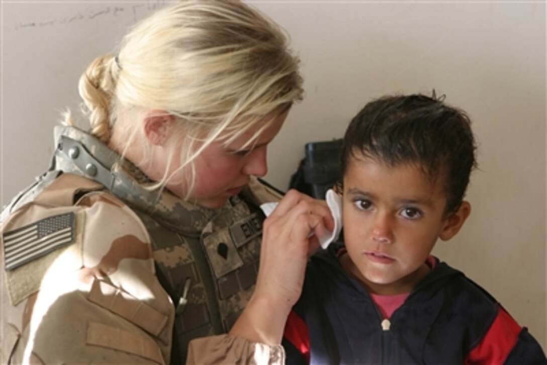 U.S. Army Spc. Taryn Emery cleans the ear of an Iraqi child during a humanitarian assistance mission in Qaryat Al Majarrah, Iraq, on Nov. 27, 2006.  Emery is attached to the Armyís 2nd Battalion, 136th Infantry Regiment.  