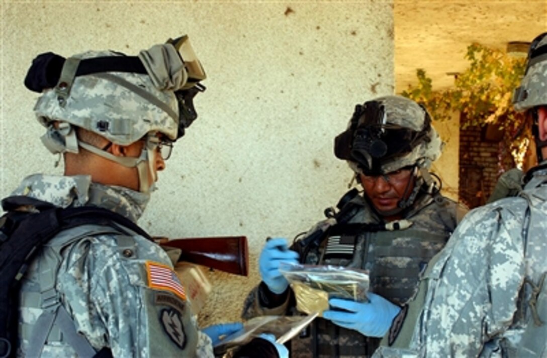 U.S. Army Pfc. Jose Baggett and Sgt. 1st Class Kenneth Franco, from the 40th Cavalry Regiment, bag and catalog evidence found during the cordon and search of a group of houses belonging to suspected improvised explosive device makers in Hawr Rajab, Al Dora province, Iraq, Nov. 29, 2006.

