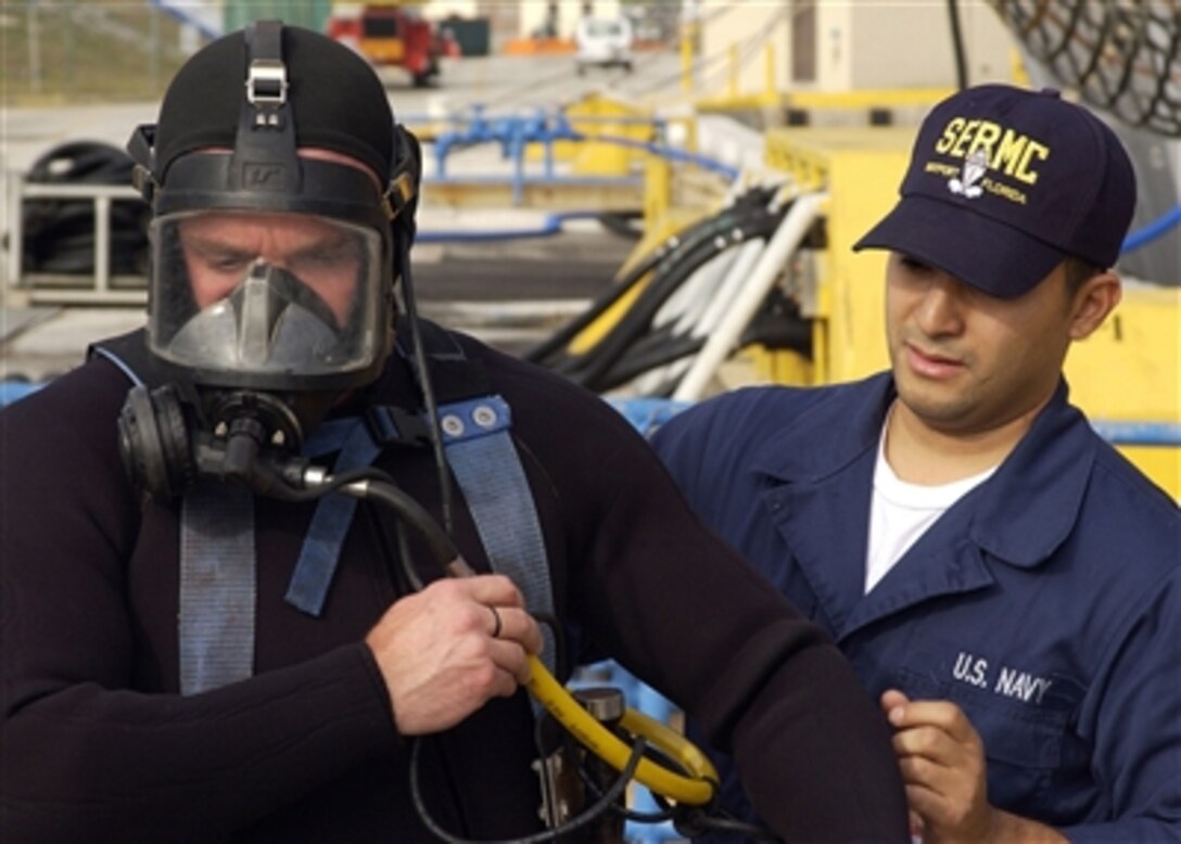 Seaman Carlos Ramirez (right) inspects Navy Diver 2nd Class Jason Eppley's diving gear before a dive in Mayport, Fla., on Nov. 29, 2006.  Eppley is preparing to install a cofferdam on the guided-missile destroyer USS Carney (DDG 64). The cofferdam is used to prevent the ship from taking on water during underwater repairs to the hull.  