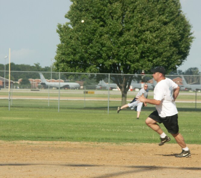 Softball brings out the best in sports fans as one player tries to steal third base, another throws him out from the far field.  Photo/Tech Sgt. Dan Oliver