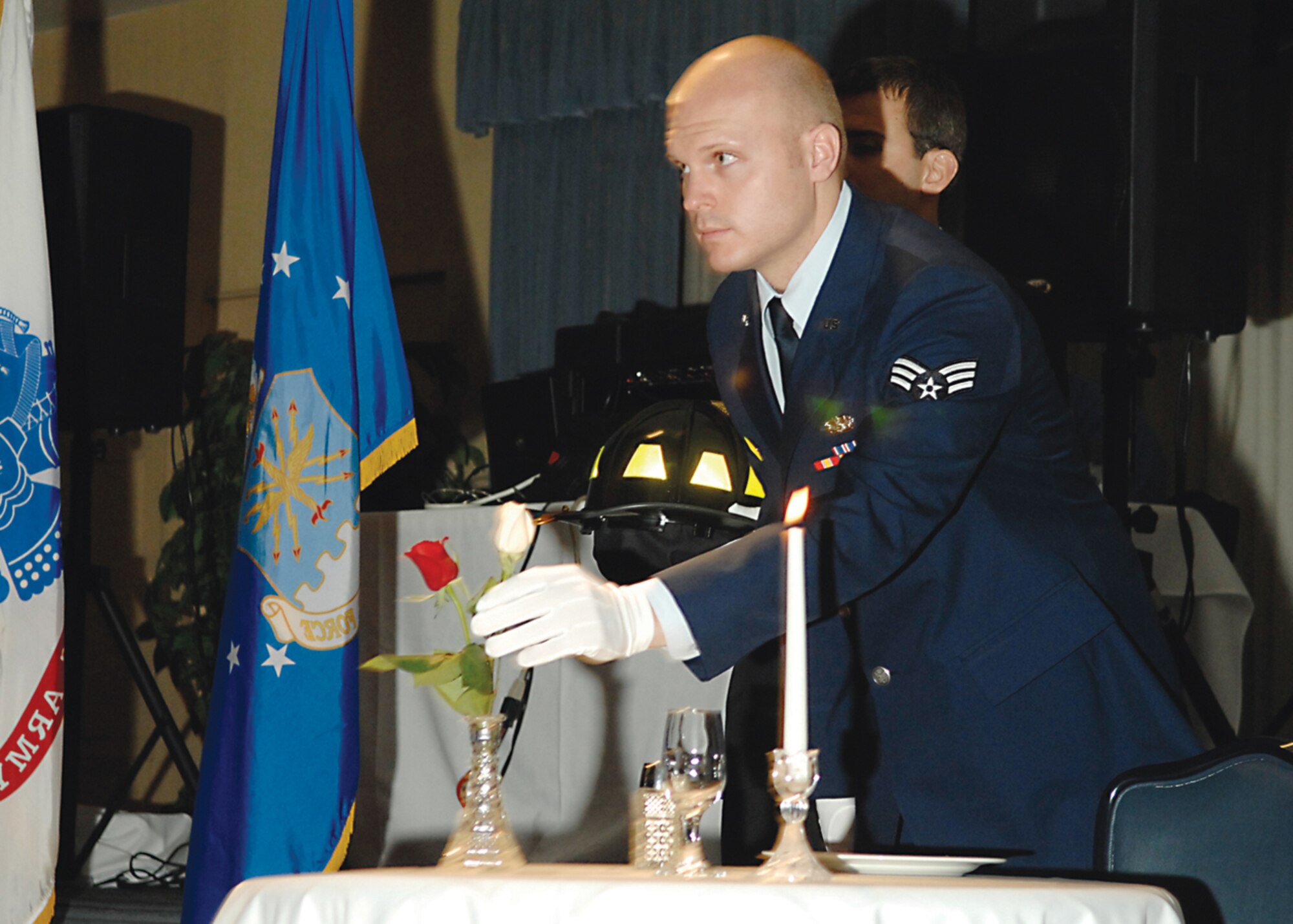 Senior Airman Christopher Lee picks up the white rose, a symbol to remind families and loved ones of firefighters who have fallen, during the Fallen Firefighter's Ceremony Nov. 18. Airman Lee, 3rd Civil Engineer Squadron, participated in the ceremony at the JBER Firefighter's Ball. (U. S. Air Force Photo by Airman First Class Jonathan Steffen)