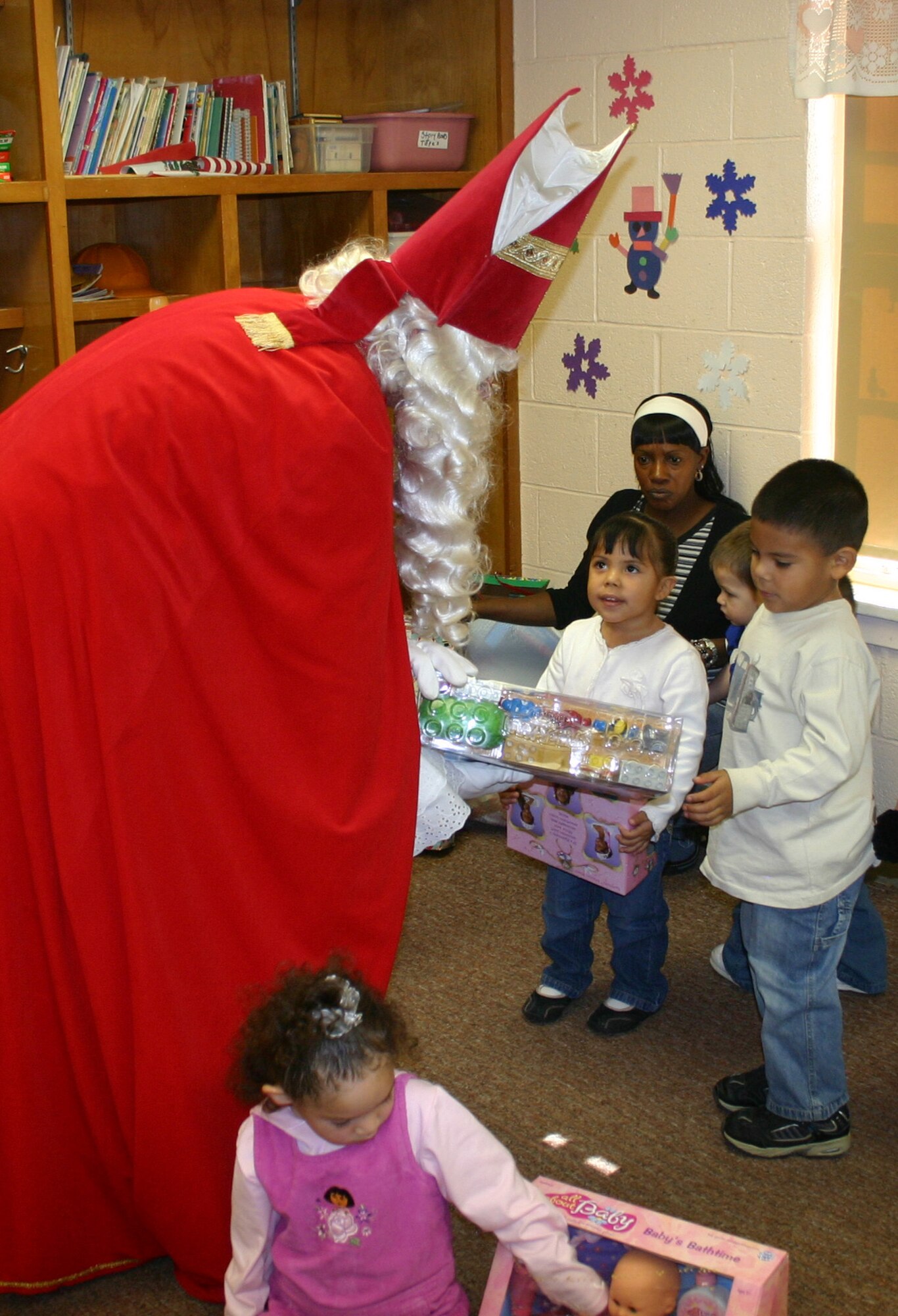 Sinterklaas hands a present to 4-year-old Joseph Torres as his sister, Alexandria, 3, watches. The Dutch community at Sheppard makes the annual trek to the Ben Donnell Day Care Center in Wichita Falls to give presents to children. (U.S. Air Force photo/Staff Sgt. Tonnette Thompson.)