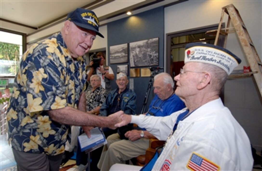 USS Oklahoma survivor Jerry Tessaro, left, shakes hands with fellow survivor Raymond Richmond during the Pearl Harbor Naval Shipyard, USS Oklahoma Lobby Display Dedication ceremony at Naval Station Pearl Harbor, Hawaii, Dec. 6, 2006.
