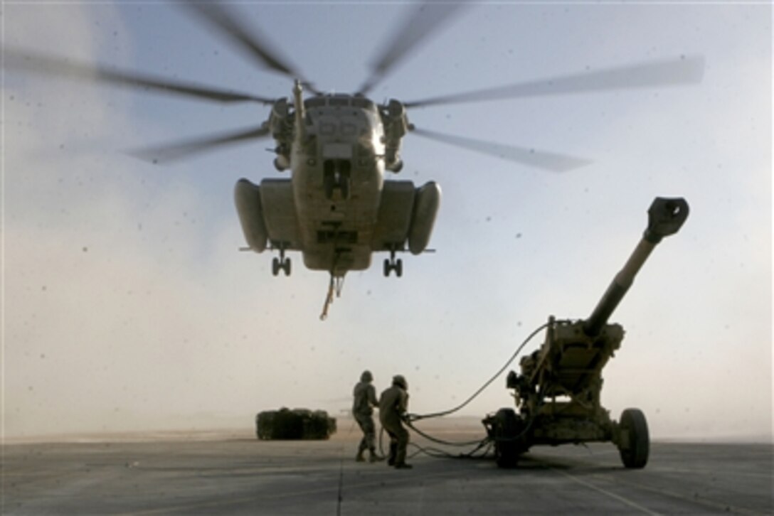 Marines prepare to attach a sling fastened to a M198 Medium Howitzer onto a U.S. Marine Corps CH-53E Super Stallion helicopter in Al Asad, Iraq, on Nov. 29, 2006.  The Super Stallion, from Heavy Marine Helicopter Squadron 465, 3rd Marine Aircraft Wing (Forward), will airlift the howitzer to Barwana, Iraq.  
