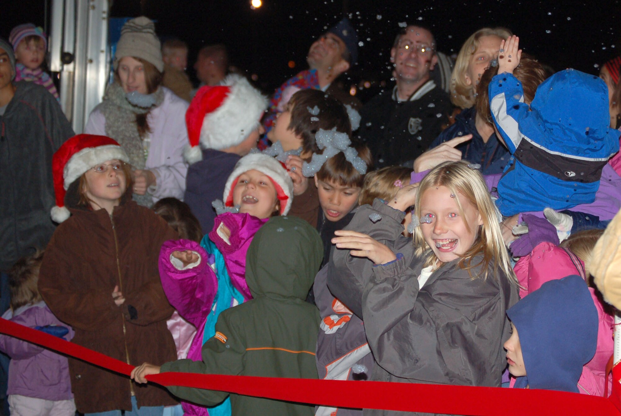 Children and adults enjoy the first "snow" of the holiday season Dec. 6, 2006, during the Edwards holiday tree-lighting ceremony. People were treated to a field of artificial snow, holiday carolers and an appearance by Santa Claus during the evening. (Photo by Airman 1st Class Julius Delos Reyes)