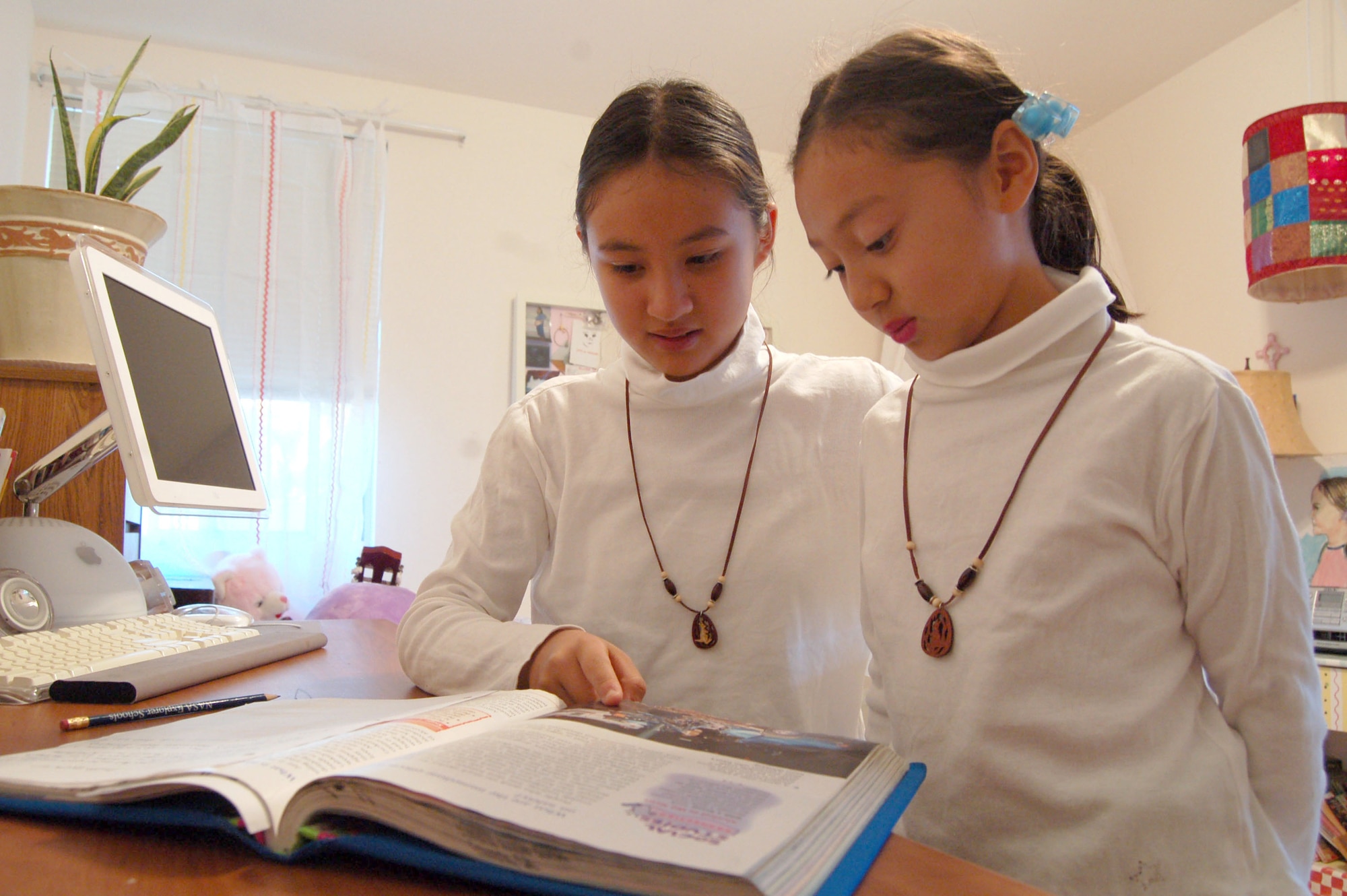 Isabella Millman (left), 11, a Branch Elementary School sixth grade student, shows her sister, Tiffany, 8, a Bailey Elementary School second grade student, her astronomy book. Isabella won second place in a national NASA essay contest. (Photo by Airman 1st Class Julius Delos Reyes)