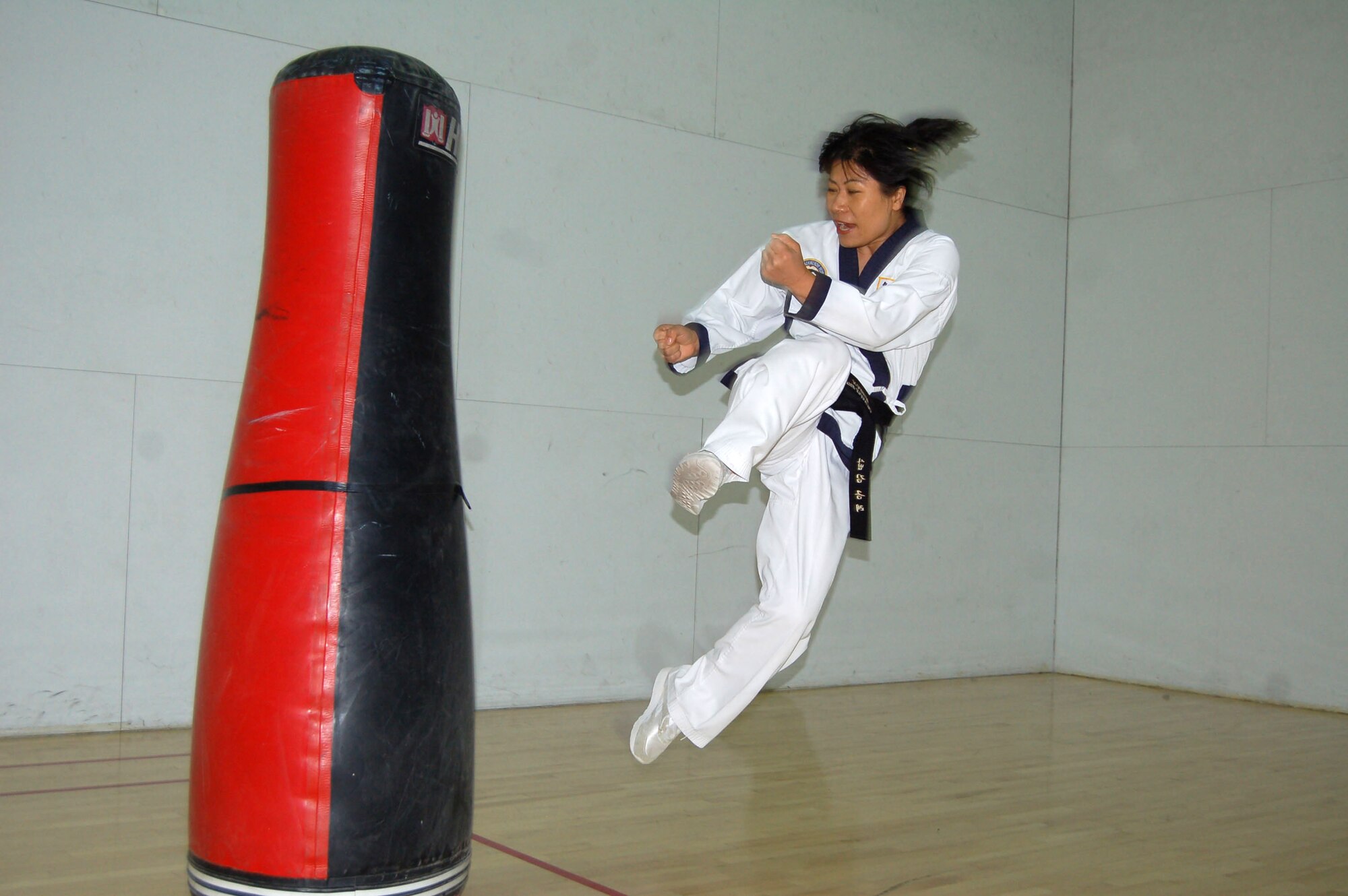 Kumye Moore demonstrates a Tae Kwon Do jumping side kick at one of her classess at the Rosburg Fitness Center on Dec. 4, 2006. Ms. Moore is a fourth Dan black belt instructor with the World Tae Kwon Do Federation. (Photo by Airman 1st Class Julius Delos Reyes)