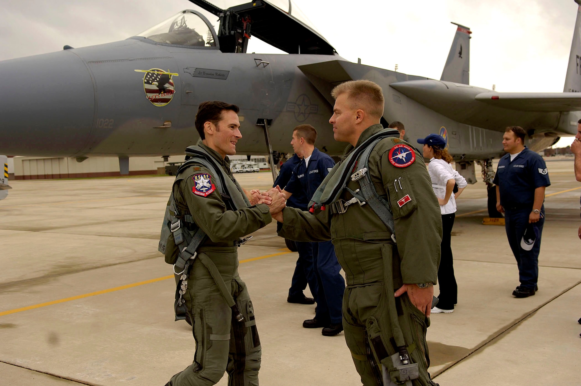 Maj. Jason Costello (right) and Maj. Paul Moga share words before the F-15 Eagle/F-22 Raptor Passing of the Torch Ceremony Dec. 1 at Langley Air Force Base, Va. The ceremony showcased the end of an era for the F-15 East Coast Demo Team and the beginning of the F-22 Raptor leading the way in aerial fighter demonstration. Major Costello is an F-15 East Demonstration team pilot, and Major Moga is the new F-22 Raptor East Coast Demonstration team pilot. (U.S. Air Force photo/Staff Sgt. Samuel Rogers) 
