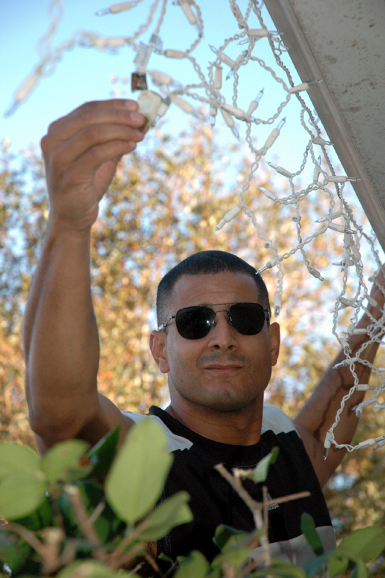 Maj. Miguel Pina, Air Force Special Operations Command Inspector General, hangs lights on his base residence Dec. 2. (U.S. Air Force Photograph by Master Sgt. Stuart Camp)
