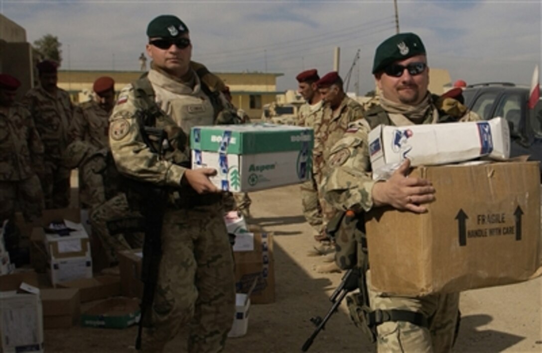 Polish army Maj. Piotr Lewandowski, left, and Warrant Officer Dariusz Drobka, both assigned to the Civil Military Cooperation Group, Multi-National Division - Central South, Camp Echo, Iraq, carry boxes of donated clothes and toys during family day at the 8th Iraqi Army Division headquarters in Diwaniyah, Iraq, Dec. 4, 2006.