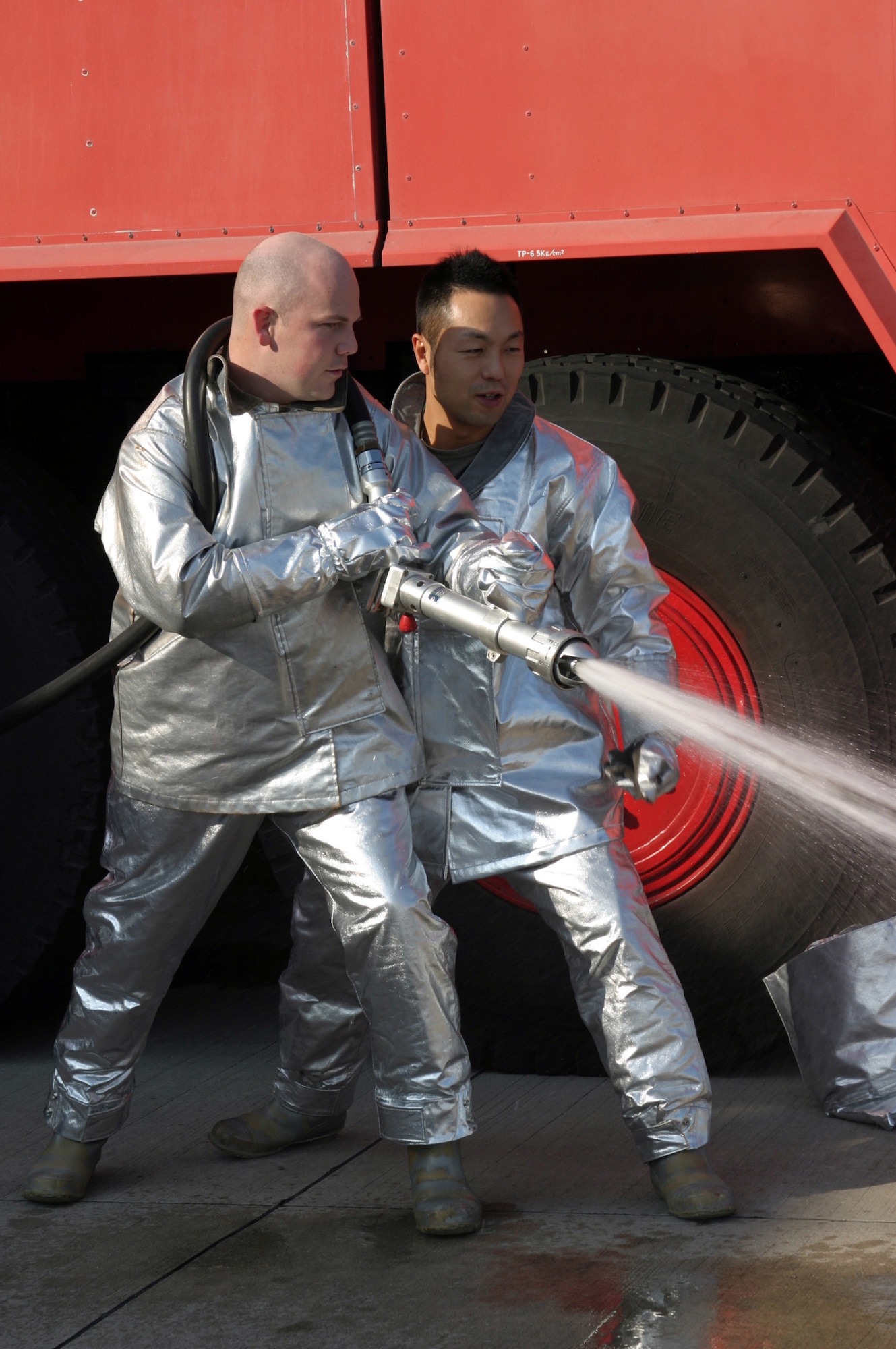 Staff Sgt. Christopher Hill learns a different technique for extinguishing fires from Japan Air Self Defense Force Master Sgt. Masashi Mitake at Tsuiki Air Base, Japan. Six Kadena Air Base, Japan, NCOs took part in a bilateral exchange from Dec. 5 to 13 at a remote seaside JASDF base. The NCOs lived and worked alongside JASDF Airmen in similar jobs to build relations and promote interoperability. Sergeant Hill is with the 18th Civil Engineer Squadron, (U.S. Air Force photo/Master Sgt. Jeffery Loftin)