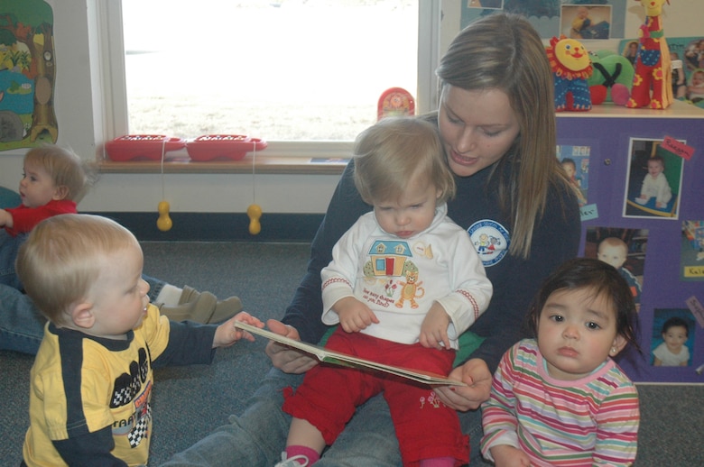 Jaci Campbell, program assistant, reads a book in one of the infant rooms in the child development center here Dec. 5. The CDC achieved high ratings during an inspection.