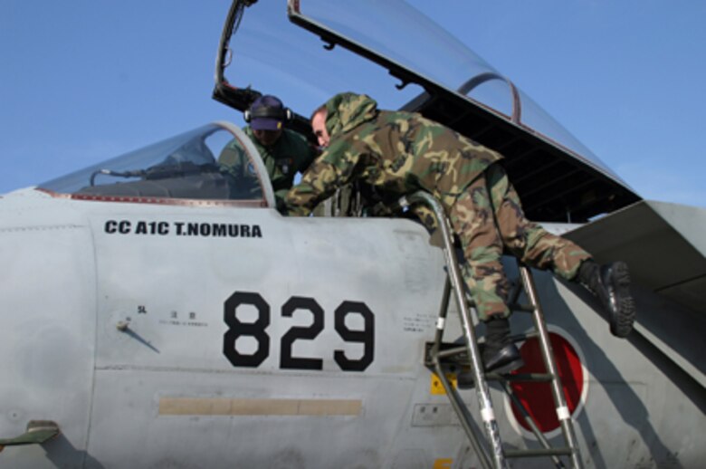 KADENA AIR BASE, Japan -- Japan Air Self Defense Force Tech. Sgt. Takafumi Funatsu gives U.S. Air Force Staff Sgt. Matthew Heaton a look at the controls of a JASDF F-15 at Tsuiki Air Base, Japan. Six Kadena NCOs took part in a bilateral exchange Dec. 5-13 at a remote sea-side JASDF base. The NCOs lived and worked alongside JASDF Airmen in similar jobs to build relations and promote interoperability. (U.S. Air Force photo/ Master Sgt. Jeff Loftin)

