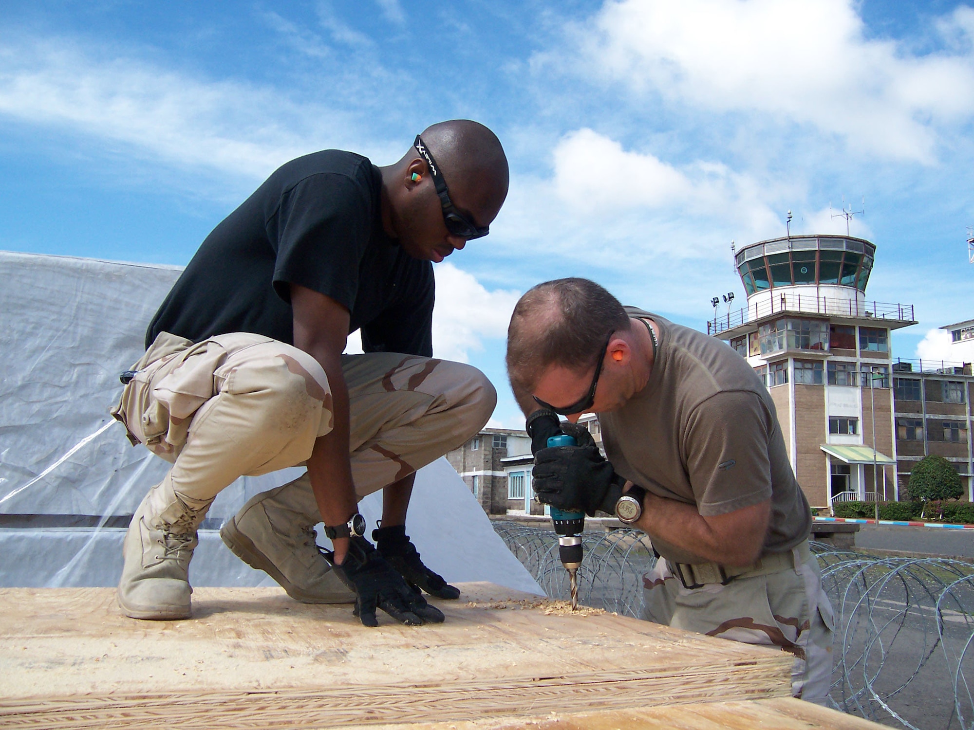 Tech. Sgt. Terreon Shirlee (left) assists Capt. James King drill holes into plywood Dec. 8 that will serve as the base for pallets being air dropped into eastern Kenya. Sergeant Shirlee is an air transportation journeyman deployed to the 386th Expeditionary Logistics Readiness Squadron from Little Rock Air Force Base, Ark., and Captain King is the commander of the movement control team at the 386th ELRS deployed from Robins AFB, Ga. (U.S. Air Force photo/Tech. Sgt. Steve Staedler)