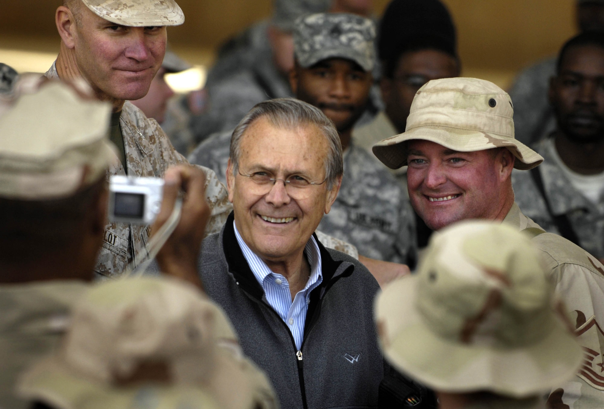 Secretary of Defense Donald H. Rumsfeld poses for a photo with servicemembers at a town hall meeting Dec. 9 on Al Asad Air Base, Iraq. Rumsfeld made a surprise visit to Iraq to thank the military members and their families for their sacrifice and dedication to the country. (Department of Defense photo/Cherie A. Thurlby) 