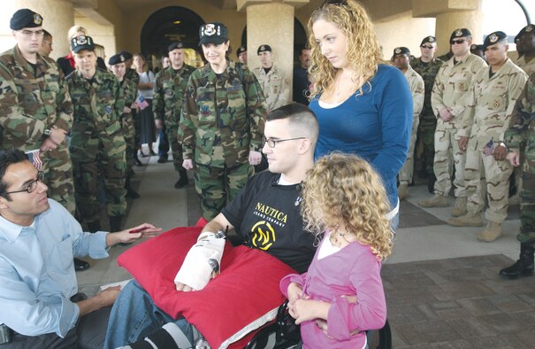 Airman 1st Class Brandon Byers, 99th Security Forces Squadron, accompanied by his wife and daughter, speaks to news media Nov. 6 in front of the Officers' Club after returning to Nellis. Airman Byers was injured by an improvised explosive device during a convoy mision while deployed to Camp Bucca, Iraq. (U.S. Air Force photo/Airman Larry Reed)