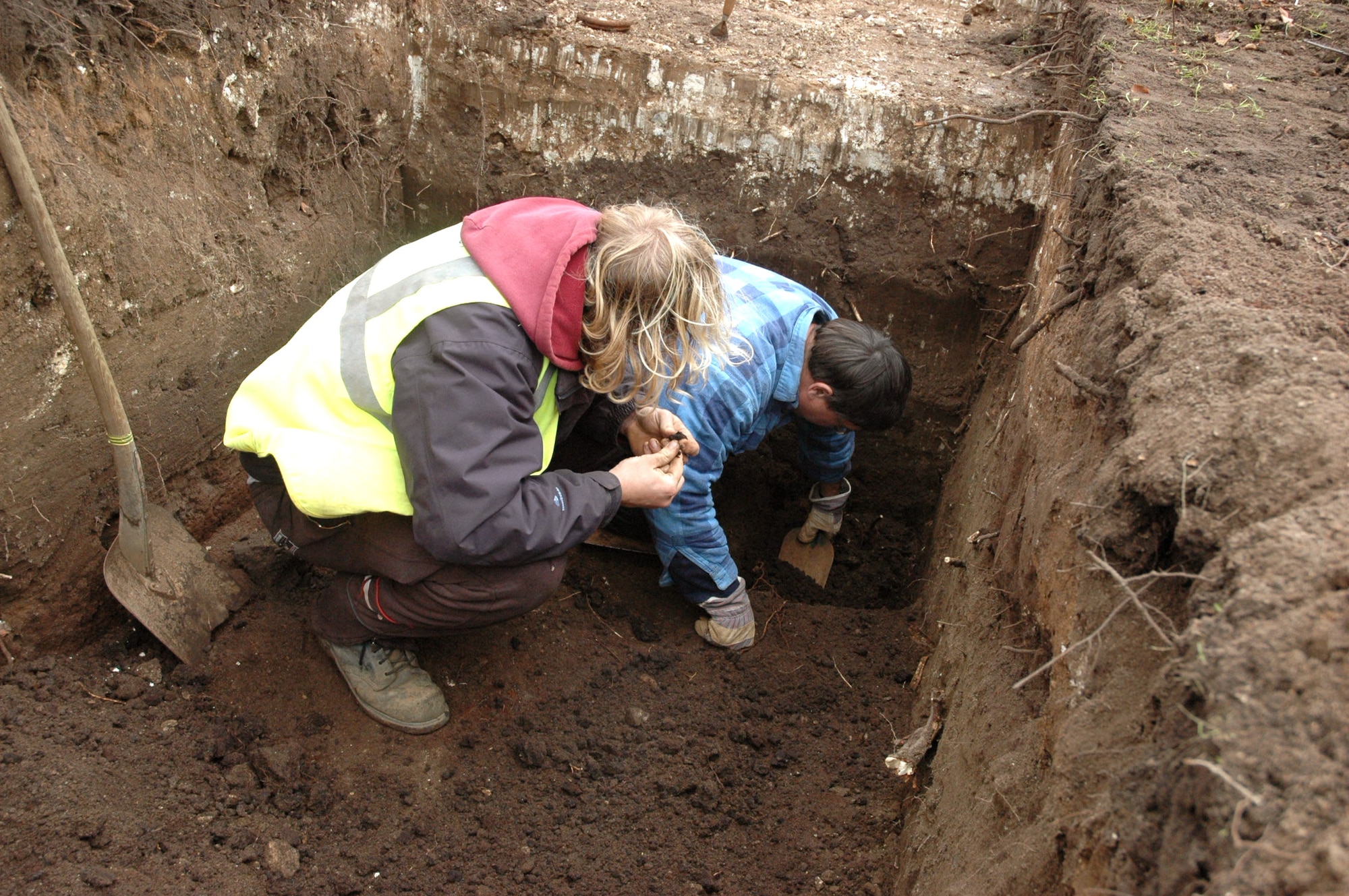 British archeologist Nick Taylor (left) inspects fragments of rock from a dig site as fellow archeologist Jonathan Van Jennians continues to dig. The trial trenches are being dug at RAF Mildenhall, England where new officer housing units are to be built. The United Kingdom requires all construction projects go through this dig to ensure no  potential historical artifacts are destoyed. (U.S. Air Force photo/Tech. Sgt. Scott Wakefield)