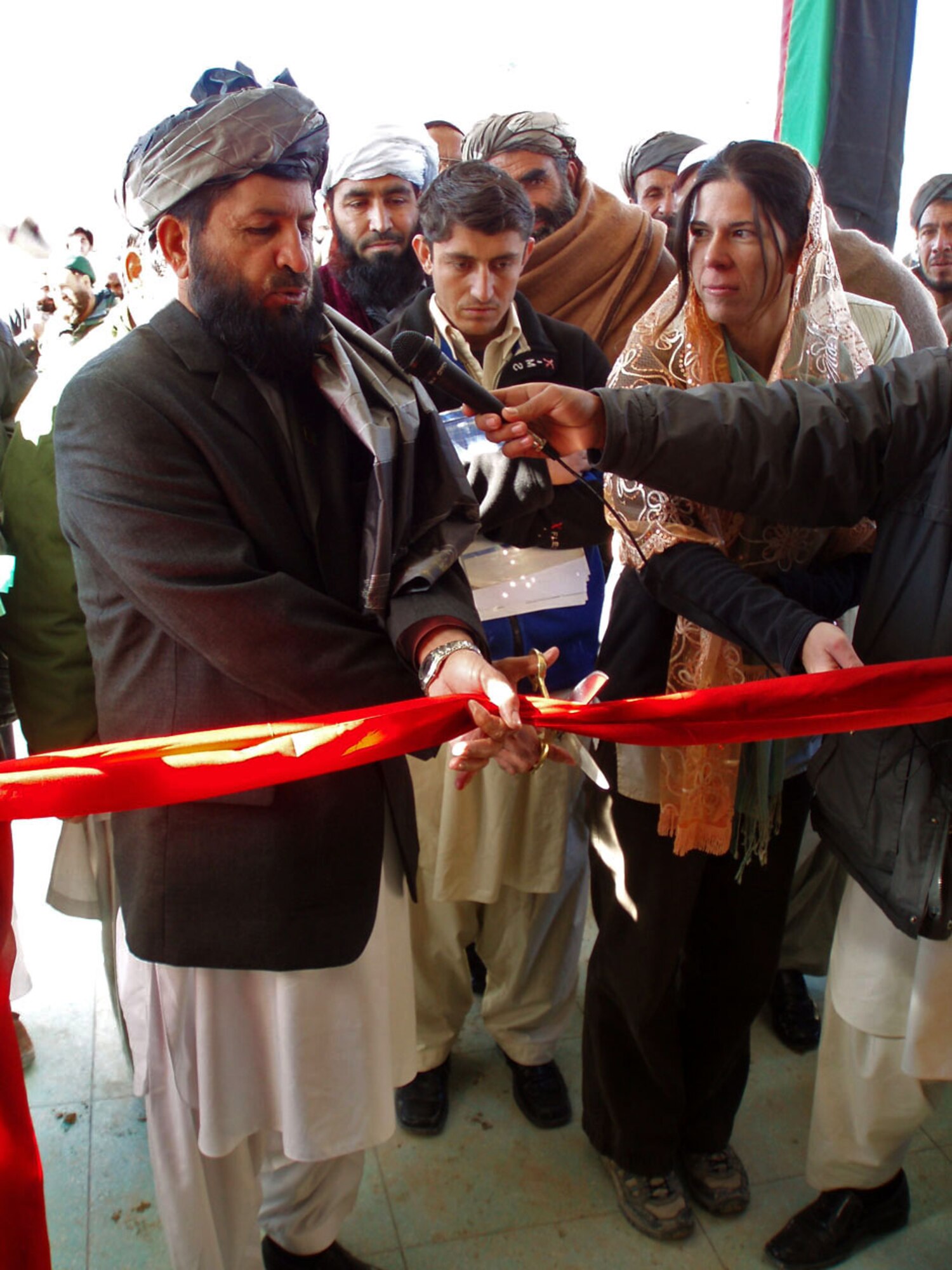 Gov. Del Bar Jan Arman, left, prepares to cut the ribbon to the new Da Afghan Bank facility in Qalat Dec. 7 as USAID Zabul representative Jennifer Ragland, right, gives a helping hand.  (Air Force photo/Capt. Kevin Tuttle)      