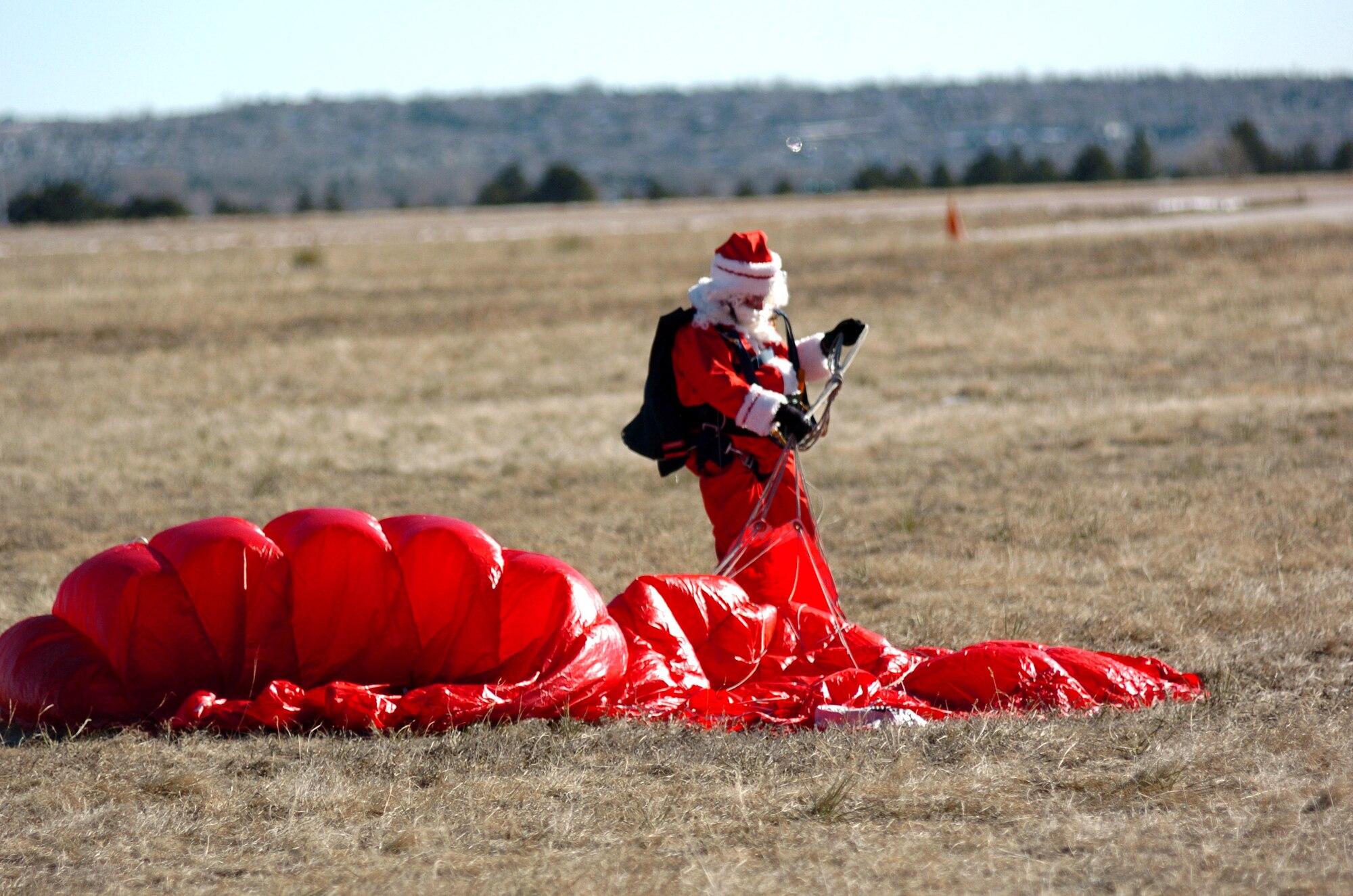 Jolly old Saint Nick gathers up his parachute after a successful jump at the U.S. Air Force Academy in Colorado Springs, Colo. Santa Claus visited the Academy Dec. 9 to learn proper egress and parachute techniques in case of a sleigh malfunction on Christmas Eve. Santa's fans can track his journey around the world on Dec. 24 at North American Aerospace Defense Command's special Web site www.noradsanta.org.The site also features the history of NORAD Tracks Santa program, has interactive games and more. (U.S. Air Force photo/1st Lt. John Ross)
