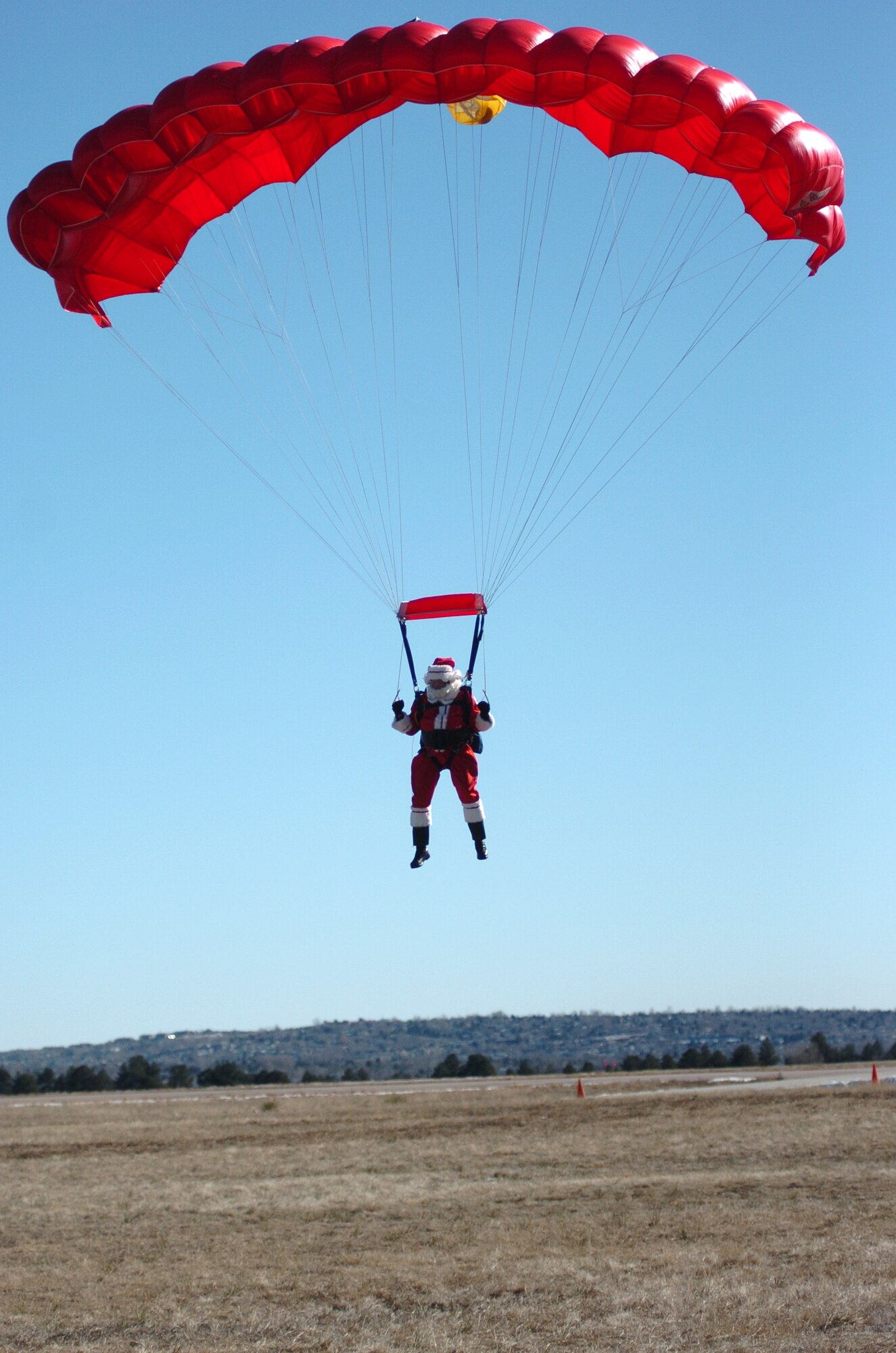 Santa Claus prepares for a perfect landing after a successful parachute jump at the U.S. Air Force Academy in Colorado Springs, Colo. Old Saint Nick visited the Academy Dec. 9 to learn proper egress and parachute techniques in case of a sleigh malfunction on Christmas Eve. Santa's fans can track his journey around the world on Dec. 24 at North American Aerospace Defense Command's special Web site www.noradsanta.org.The site also features the history of NORAD Tracks Santa program, has interactive games and more. (U.S. Air Force photo/1st Lt. John Ross) 

