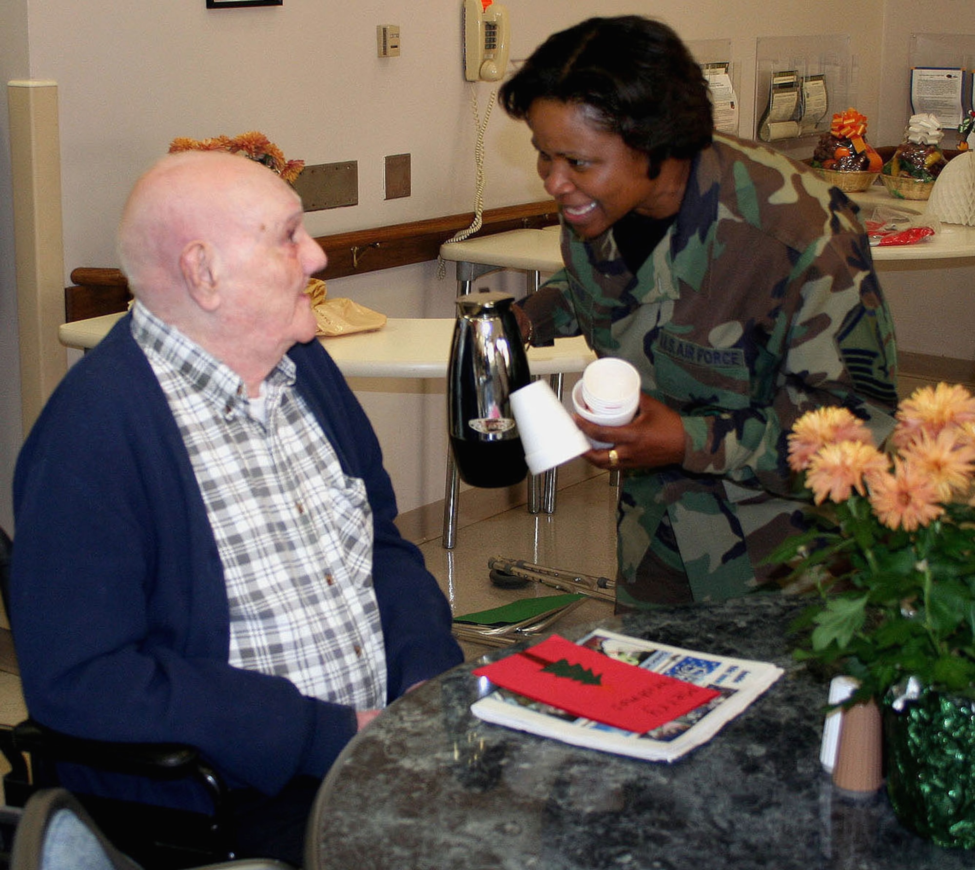 DAYTON, Ohio – Master Sgt. Cynthia Holland from the 445th Airlift Wing Headquarters ask veteran Julius Hatch if he would like some coffee while visiting the Dayton Administration Nursing Home during their holiday party. (U.S. Air Force photo/Maj. Jose Cardenas).
