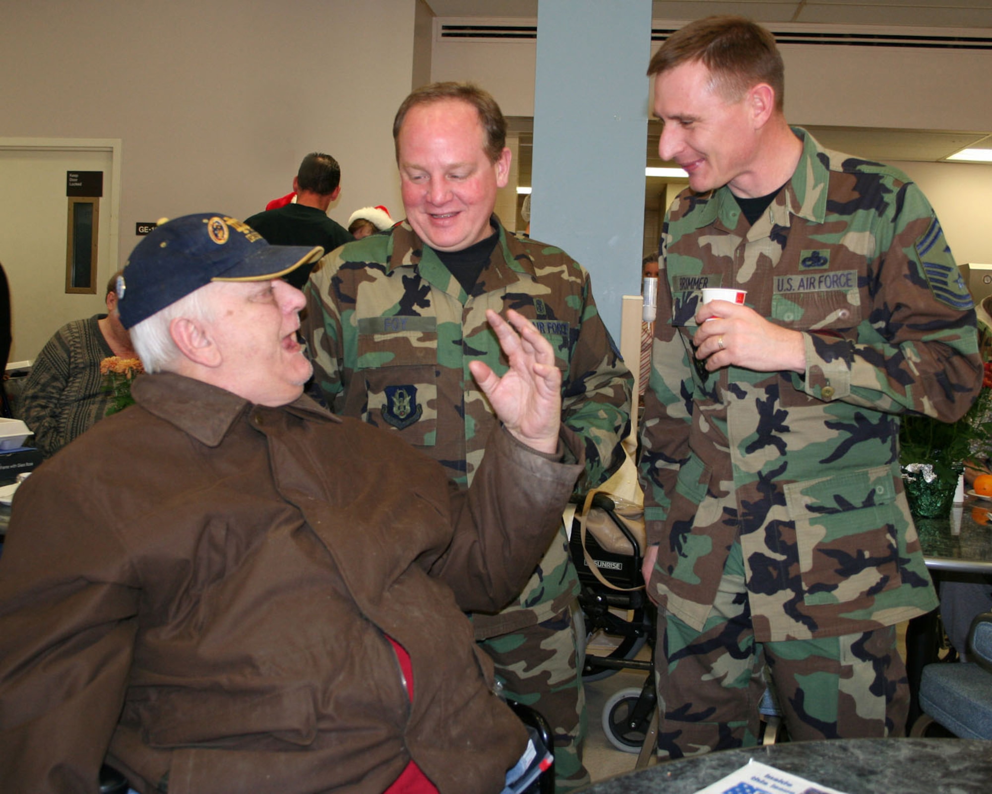 DAYTON, Ohio -- Veteran Walter Shelhorn talks to Master Sgt. Jim Foy (center) and Senior Master Sgt. Mike Brimmer (Left) during a visit at the Dayton Veterans Administration Nursing Home during their annual holiday party. (U.S. Air Force photo/Maj. Jose Cardenas).