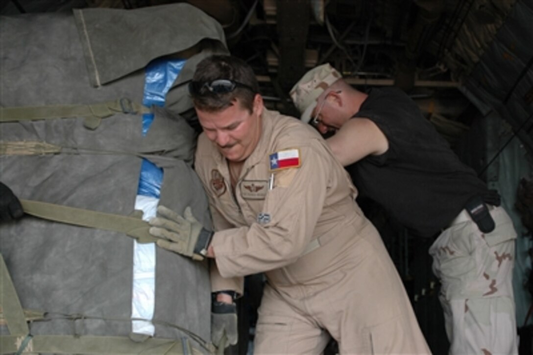 U.S. Air Force Staff Sgt Patrick Delselva, deployed to the 746th Expeditionary Airlift Squadron, uses some muscle to position a pallet filled with tarps, tents and mosquito netting on a C-130 in Dadaab, Kenya, Dec. 9. The Air Force is air dropping supplies to flood refugees in Eastern Kenya. 