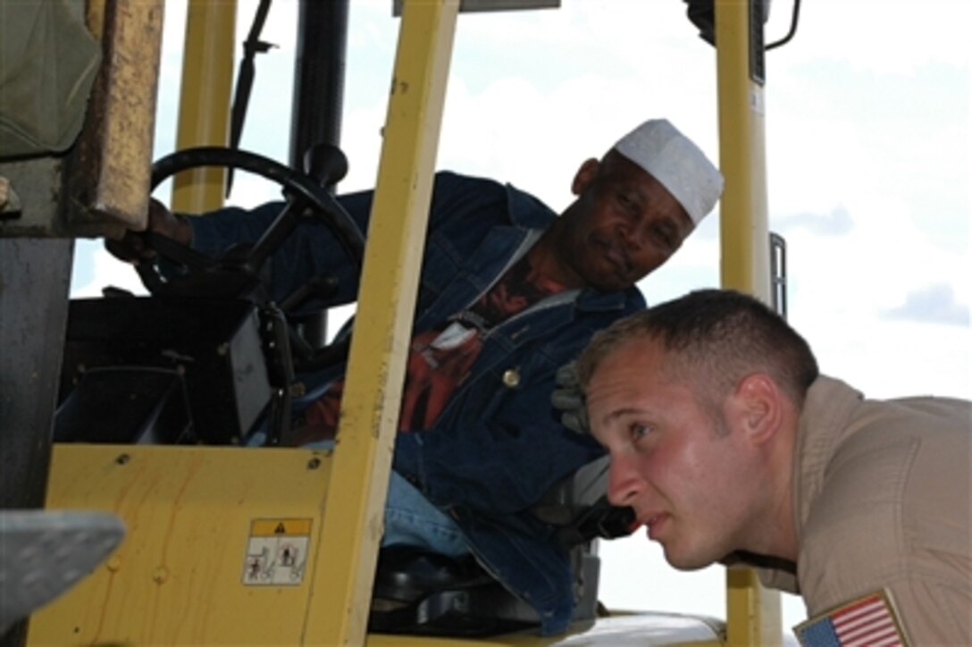 U.S. Air Force Senior Airman Chris Elder, a loadmaster from Dyess Air Force Base, Texas, deployed to the 746th Expeditionary Airlift Squadron, guides the driver of a forklift carrying a pallet of tents, tarps and mosquito netting onto an awaiting C-130 Hercules, in Dadaab, Kenya, Dec. 9.