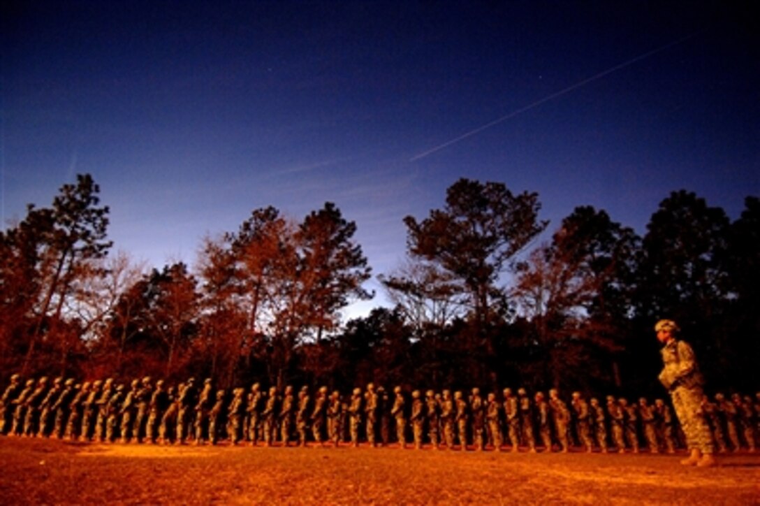 A U.S. Army basic training instructor, right, watches over recruits that are lined up waiting to begin their night infiltration course during U.S. Army basic training at Fort Jackson, S.C., Dec. 5, 2006.