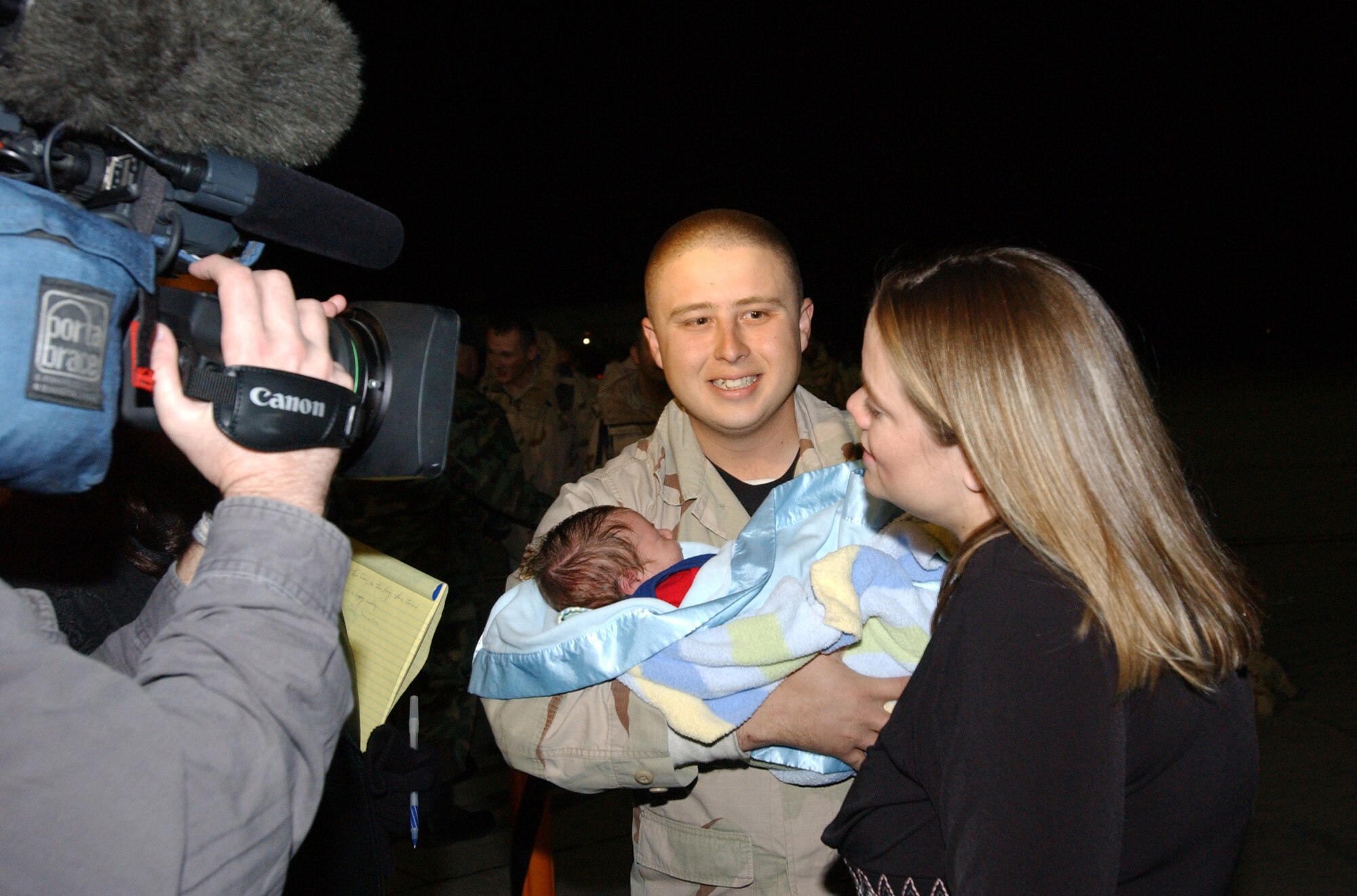 Senior Airman Anthony Navejas, 99th Security Forces Squadron, is greeted by his wife, Jessica, and 12-day-old son, Hayden,  as he returns to Nellis Air Force Base, Nev., after an eight-month deployment to Iraq. Seventy-two security forces Airmen returned to Nellis Dec. 12. (U.S. Air Force photo/Staff Sgt. Jeremy Smith)  