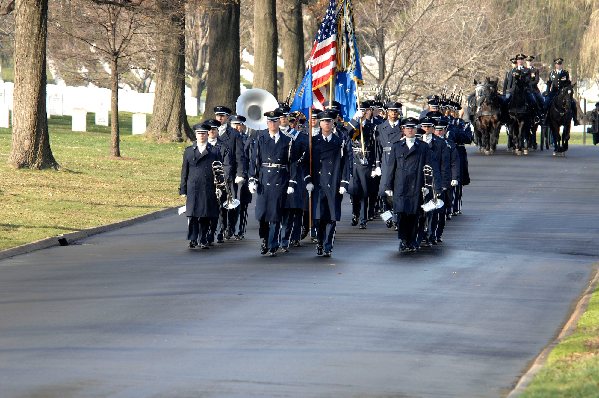 The Air Force Band and Honor Guard lead a funeral procession comprised of the Army Cason and friends and relatives of Capt. Kermit Evans Dec. 12 at Arlington National Cemetery. The cason are transporting the body of Captain Evans while more than 200 friends and relatives follow along to pay their respects to the former member of the 27th Civil Engineering Squadron Explosives Ordnance Disposal Flight at Cannon Air Force Base, N.M. He was deployed to Iraq when the helicopter he was a passenger in made an emergency landing and crashed. He was one of the four out of 16 who were killed as a result of the crash. He is survived by his wife, Perneatha, and Kermit Jr., their 13-month-old son.(U.S. Air Force photo/Tech. Sgt. Cohen Young) 