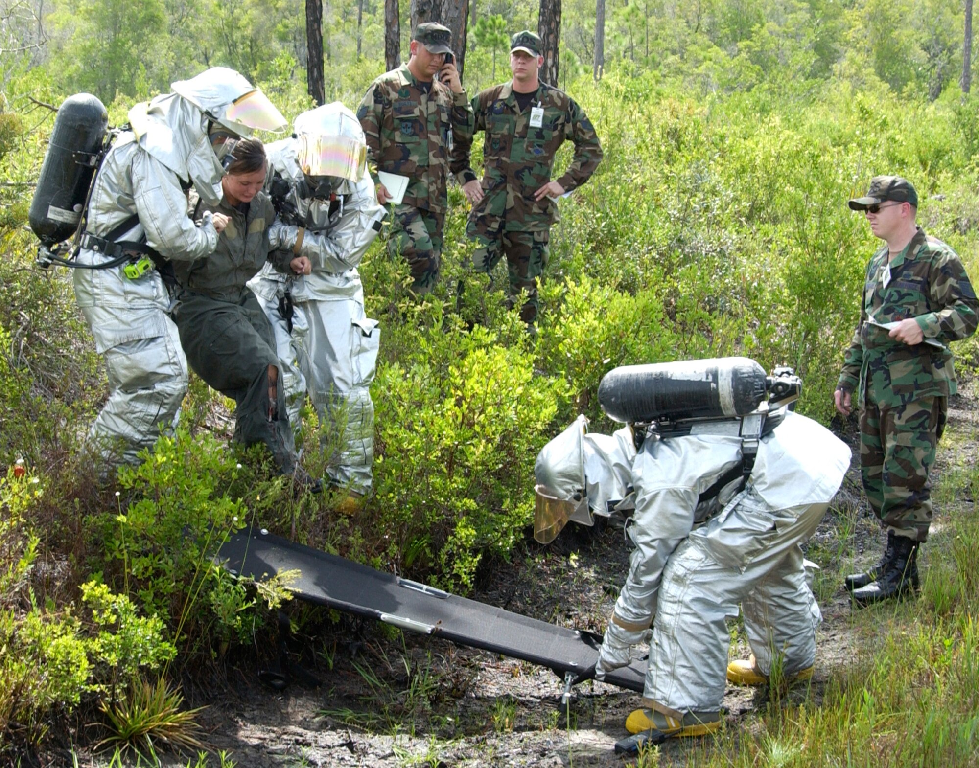 TYNDALL AIR FORCE BASE, Fla. --  As evaluators look on, Tyndall fire fighters pull an “injured” pilot from the woods in a major accident response exercise that took place July 25. Senior Airman Yvonne Smith, 325th Fighter Wing exercise plans information manager, simulated an F-22 Raptor pilot who crashed upon approach to the runway. (U.S. Air Force photo by Lisa Norman)