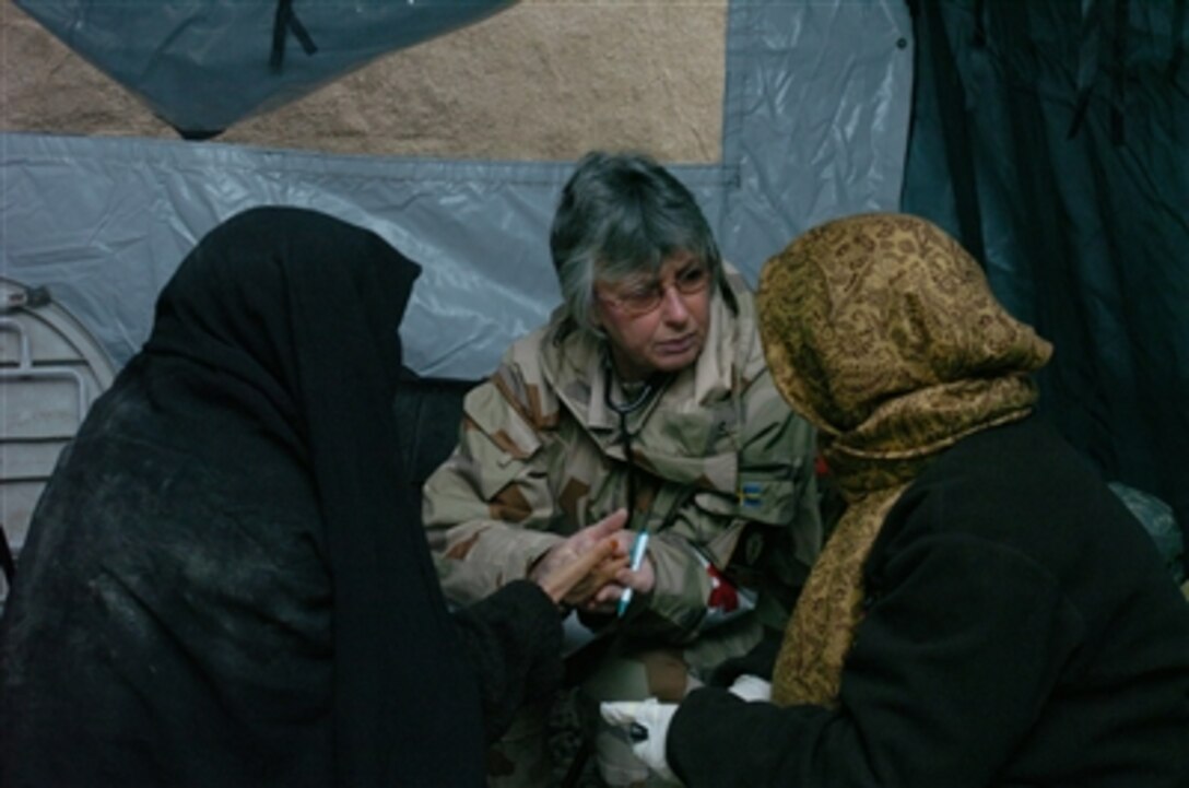 A Norwegian army doctor looks to her interpreter for a translation of an Afghan woman's complaints during a medical civil action project in the Mazar-e Sharif region of Afghanistan, Nov. 28, 2006.