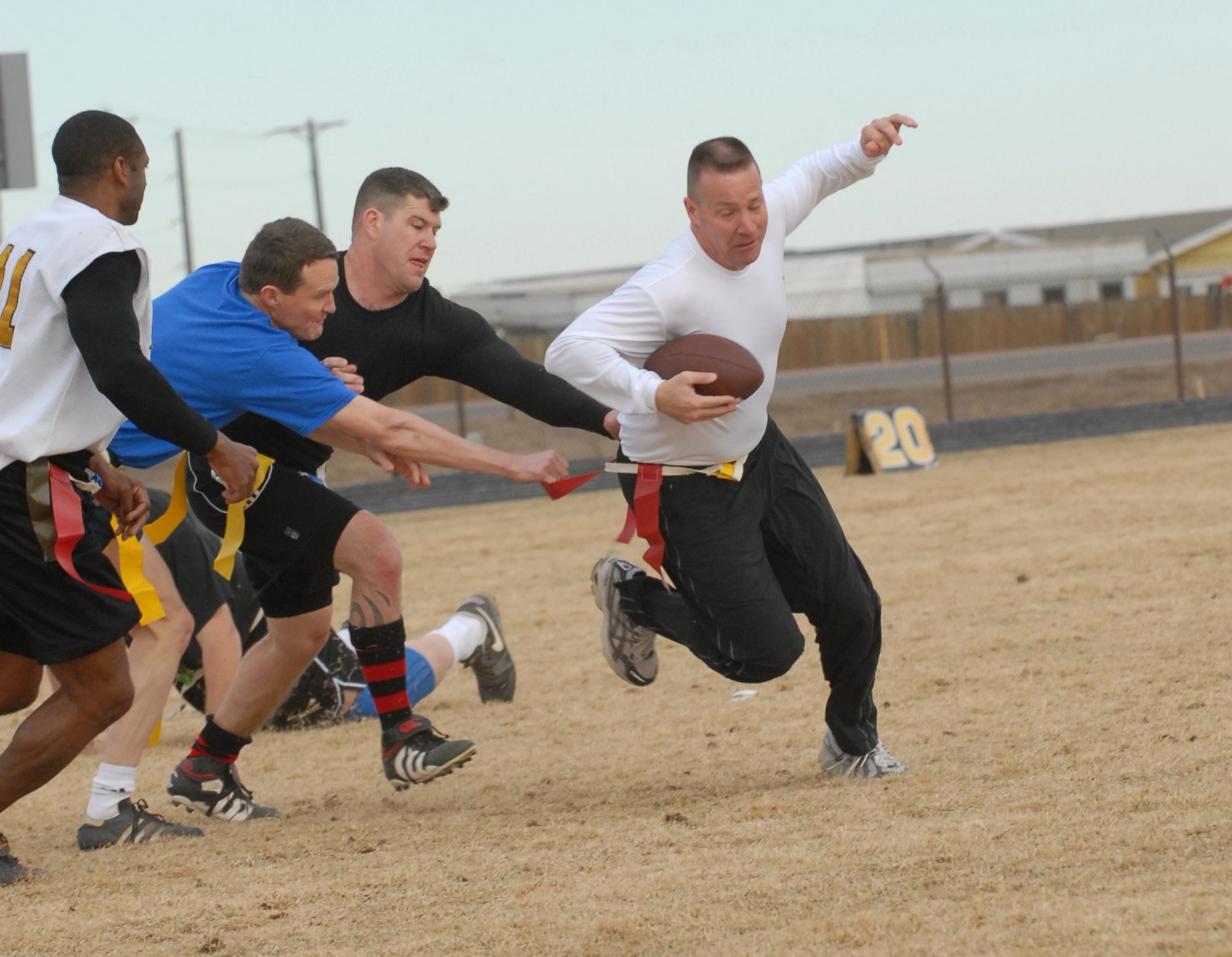 Chief player Kevin Candler tries to squeeze by Eagle members Jeff Beckford and David Ziegler during a flag football game between Buckley chiefs and first sergeants against Buckley colonels and commanders Dec. 14. The Chiefs/Shirts won 31-0. (U.S. Air Force photo by Airman 1st Class Alex Gochnour)