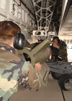 Airman 1st Class Robert Pennock and Staff Sgt. Christopher Croley, 9th Aircraft Maintenance Unit, guide a GBU-10 bomb into locking position on an F-117A Nighthawk during a Weapons Load Crew of the Quarter competition Dec. 8. (U.S. Air Force photo by Airman Jamal Sutter)