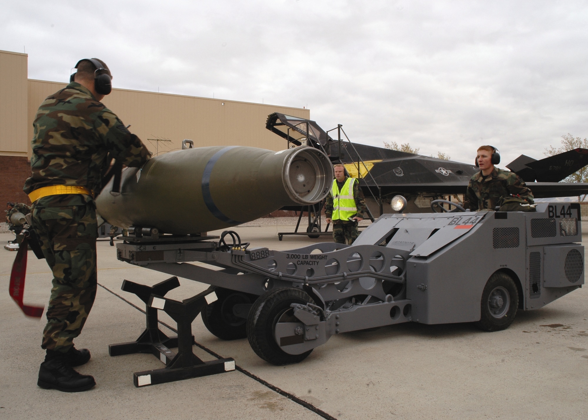 Staff Sgt. Jason Compton, 8th Aircraft Maintenance Unit holds a GBU-10 bomb steady as Airman 1st Class Jacob Johnson maneuvers an MJ-1 bomb lift truck to transport the bomb from the rack to the F-117A during the Weapons Load Crew of the Quarter competition Dec. 8. The grey jammers, as the MJ-1 is also known, made its competition debut from the original dark green color.  (U.S. Air Force photo by Airman Jamal Sutter)