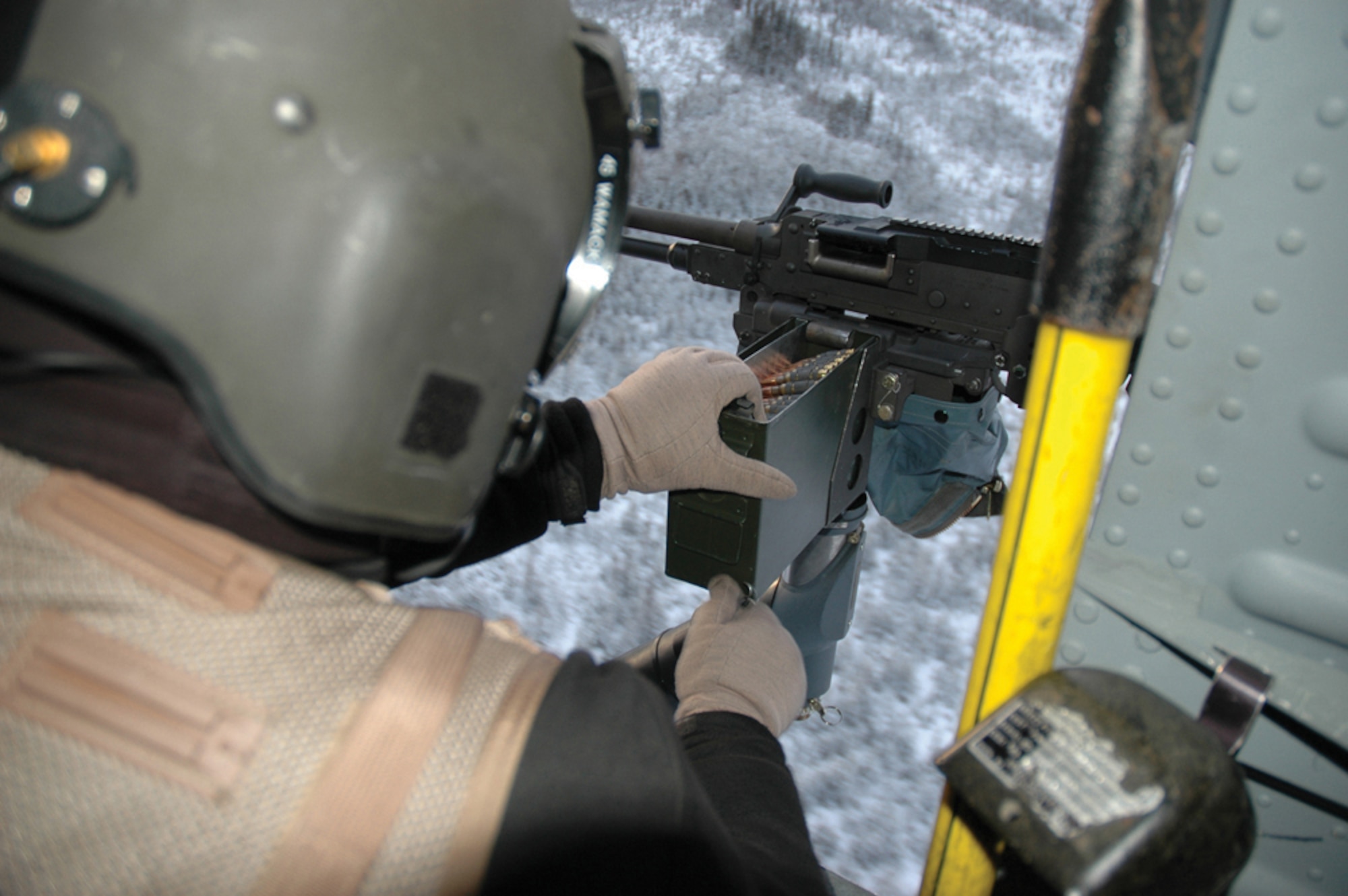 EIELSON AIR FORCE BASE, Alaska--Senior Airman Eli Wamack, Det. 1, 210th Rescue Squadron helicopter flight engineer, loads rounds into a M240 machine gun during the Dec. 7 training mission. (U.S. Air Force photo by Airman Nora Anton)