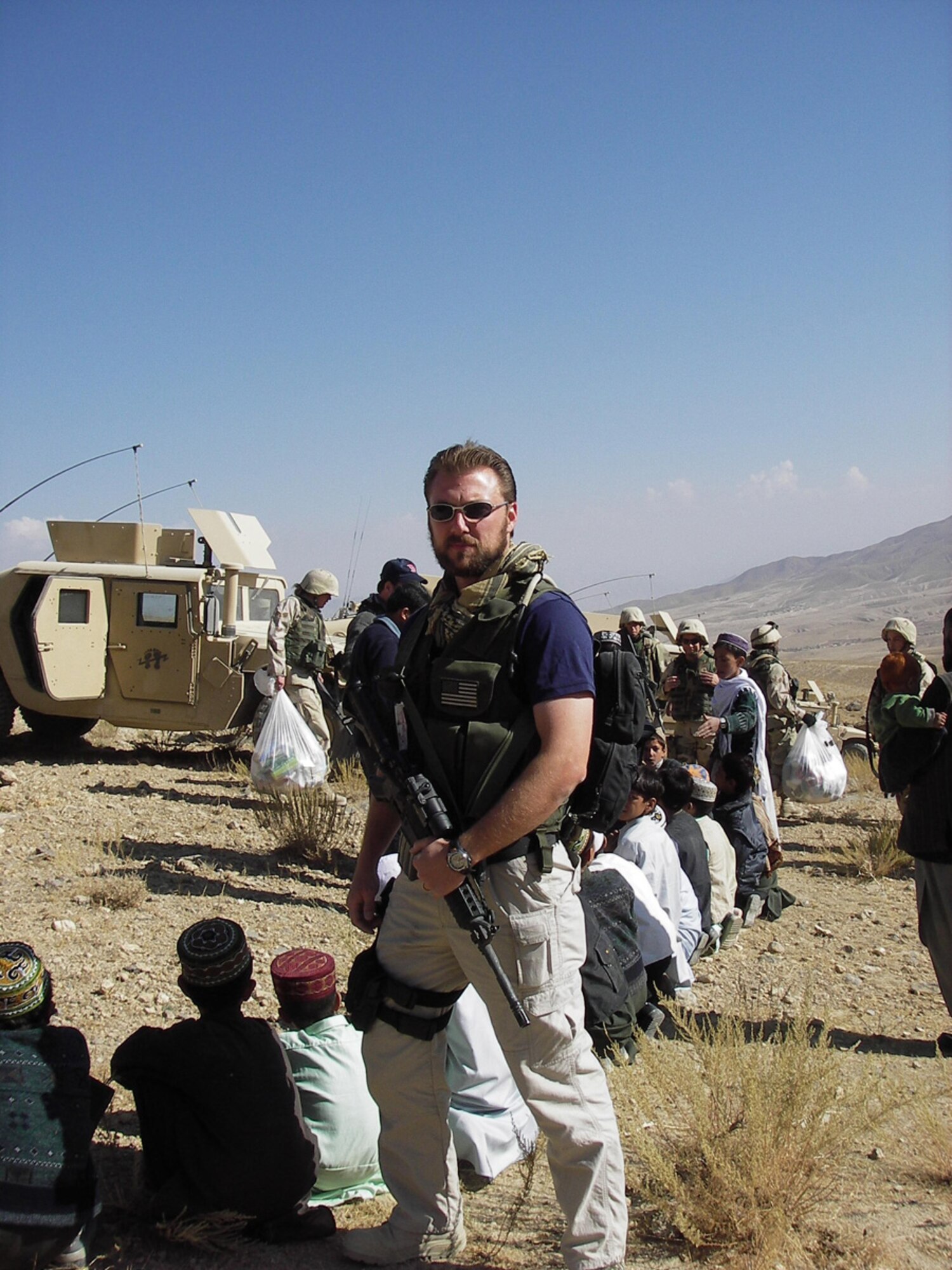 AFGHANISTAN -- Air Force Office of Special Investigations Special Agent Geoffrey Keller, Expeditionary Detachment 2405, stands guard as U.S. Forces distribute aid to local children. Agent Keller, who is stationed at Hanscom, will be presented the Bronze Star Medal Wednesday. (Courtesy photo)