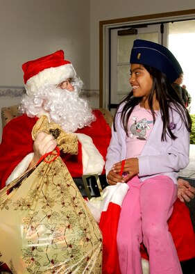 Santa Clause gives 7-year-old Violeta Guia her bag of Christmas goodies at Vandenberg's Pacific Coast Club during Operation Kids Christmas December 9, 2006.   OKC provided more than 200 underpriveledged children Christmas presents and a holiday dinner gift certificate.  The event is made possible through multiple fundraising events and corporate sponsors.  This was the 47th annual OKC at Vandenberg.  (U.S. Air Force photo by Airman Stephanie Longoria)