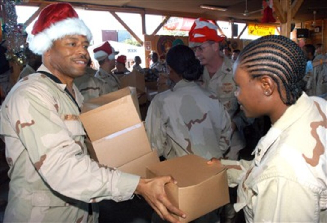 U.S. Navy Senior Chief Yeoman Shawn Newcoste, left, hands out Christmas gifts to junior enlisted U.S. servicemembers assigned to Combined Joint Task Force - Horn of Africa at Camp Lemonier, Djibouti, Dec. 10, 2006.