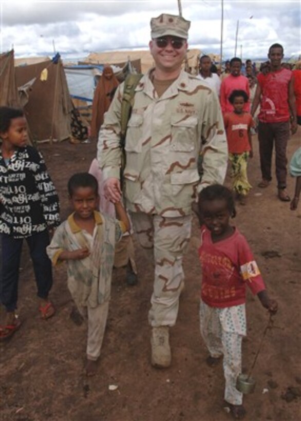 U.S. Navy Lt. Cmdr. Jeff Weitz walks holding hands with two children who live in a tent city set up by Combined Joint Task Force-Horn of Africa after severe flooding in Dire Dawa, Ethiopia, on Dec. 2, 2006.  The Joint Task Force is a unit of United States Central Command that is providing humanitarian aid and training to assist partner nations to combat terrorism.  