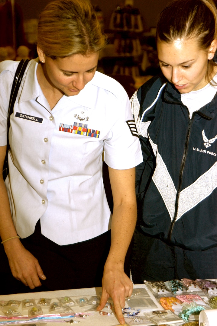 Sisters Staff Sgt. Mindy Satchwell, 37th Mission Support Squadron, and 2nd Lt. Nicole Pierce, 37th Contracting Squadron, check out the jewelry at Emmy's Gifts, a vendor table at the arts and crafts festival Dec. 15. This is the second year Mary Jockers has brought her jewelry to the annual Christmas Craftsfest on Lackland Air Force Base, Texas.  (USAF photo by April Blumer)                     