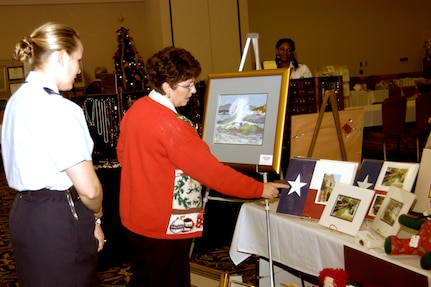Charlotte Nelms of San Antonio, Texas, tells Maj. Rebecca Lehr, 59th Training Squadron, how a squadron coin fits perfectly in the middle of the star. Ms. Nelms was one of more than 20 vendors at the annual Christmas Craftsfest on Lackland Air Force Base, Texas, Dec. 15.  (USAF photo by April Blumer)                             