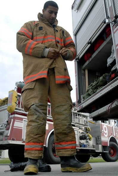 KADENA AIR BASE, Japan -- Airman 1st Class Terry Roberts Jr. puts his gear on during a training event Wednesday Dec. 13, 2006 at Kadena Air Base, Okinawa, Japan.  Airman Roberts is an 18th Civil Engineer Squadron firefighter and will be on duty during the holiday season.  (Photo by Airman 1st Class Sheila DeVera) 