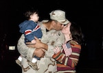 While holding his 13-month-old son, Gabriel, Staff Sgt. Matthew Rodriguez, 37th Security Forces Squadron, receives a loving "welcome home" kiss from his wife, Polly Rodriguez. Sergeant Rodriguez returned home from a six-month deployment Sunday evening with more than 110 other Airmen from across the Air Force. (Photo by Alan Boedeker)                               