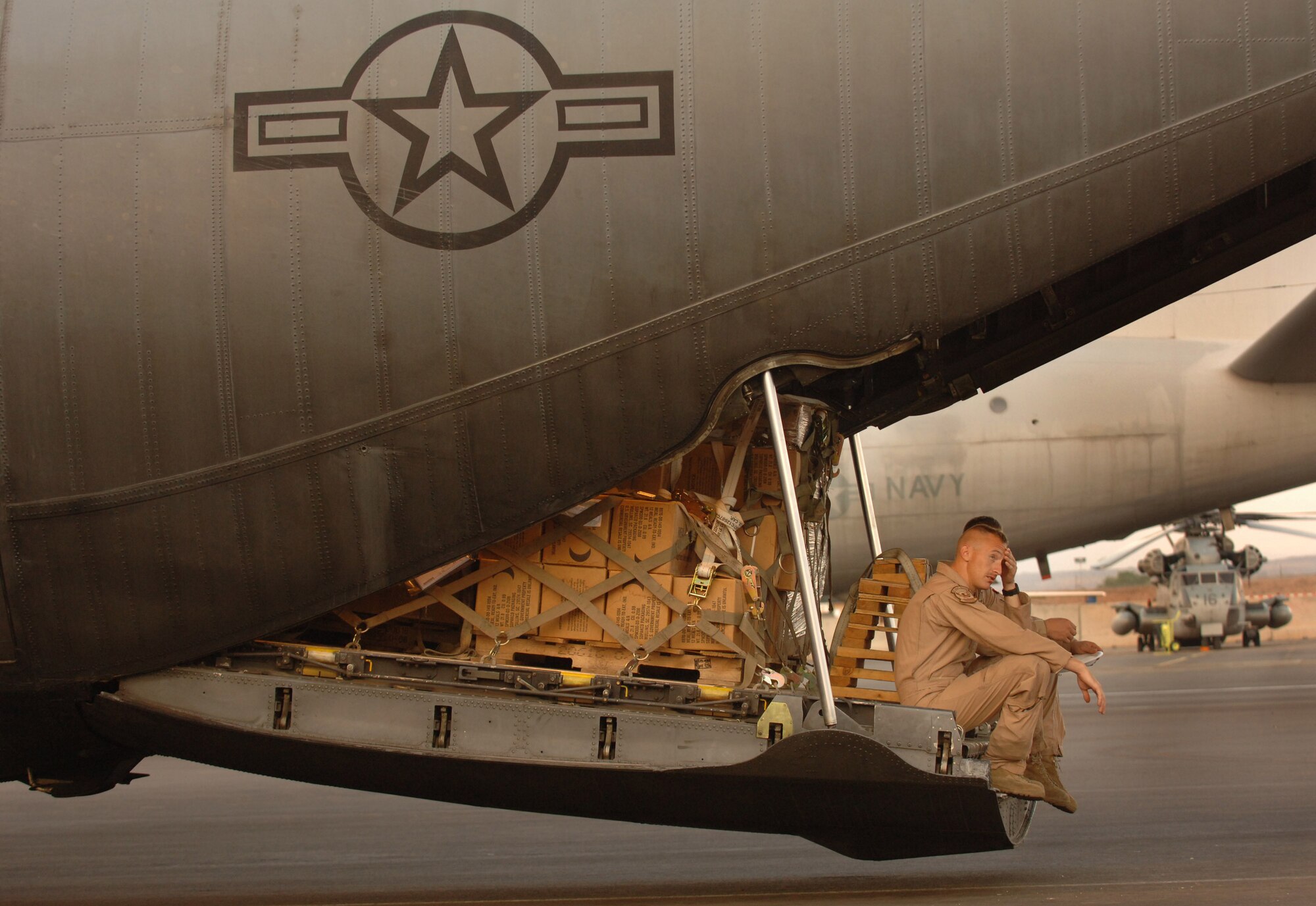 Senior Airman Brandon Davis sits on the ramp of a C-130 Hercules waiting on the tarmac to take off with supplies Dec. 13 bound for Nairobi from Camp Lemonier, Djibouti. Airman Davis is a loadmaster deployed from Dyess Air Force Base, Texas. Airmen assigned to the Combined Joint Task Force - Horn of Africa help prevent conflict, promote regional stability and protect coalition interests in order to prevail against extremism. More than 1,500 people from each branch of the U. S. military, civilian employees, coalition forces and partner nations make up the organization. (U.S. Air Force photo/Master Sgt. Scott Wagers)