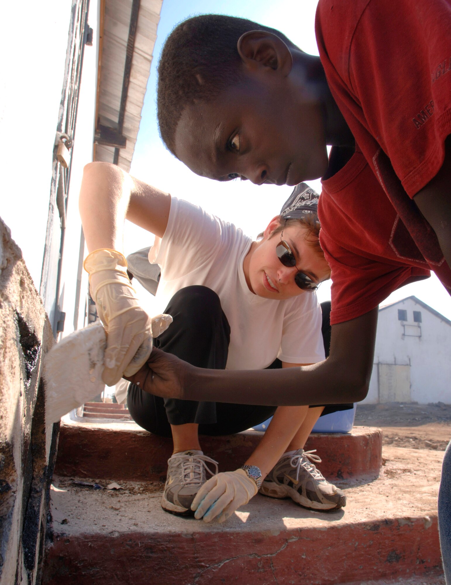 Tech. Sgt. Cassandra Stevens offers 10-year-old "Ramadan" some finer points in painting a building that will serve as a kitchen and dining facility for nearly 30 local youths Dec. 12 in Djibouti. Sergeant Stevens, an aeromedical technician from the Delaware Air National Guard, spends her spare time volunteering at a Djibouti boy's orphanage. Airmen assigned to the Combined Joint Task Force - Horn of Africa help prevent conflict, promote regional stability and protect coalition interests in order to prevail against extremism. More than 1,500 people from each branch of the U. S. military, civilian employees, coalition forces and partner nations make up the organization. (U.S. Air Force photo/Master Sgt. Scott Wagers)