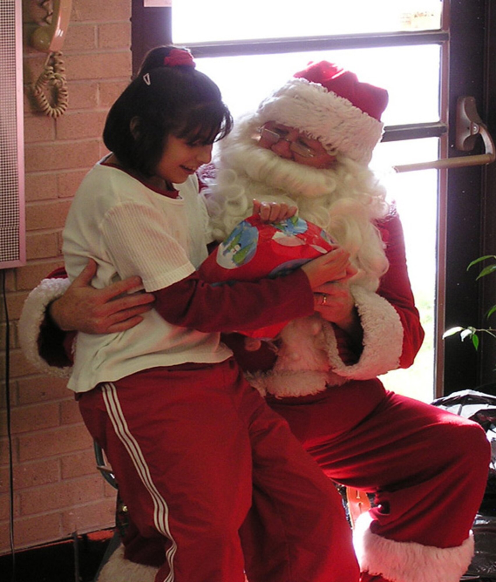 Mound Fort Middle School student, Mercedes De La Fuente, sits on Santa’s lap Nov. 30 when he and members of the 67th Aerial Port Squadron visited the school to deliver Christmas gifts.  The 67th APS has arranged for Santa to make an appearance at the school to deliver gifts for the class for the past 16 years. (U.S. Air Force Photo/Tech. Sgt. Henry Beck)