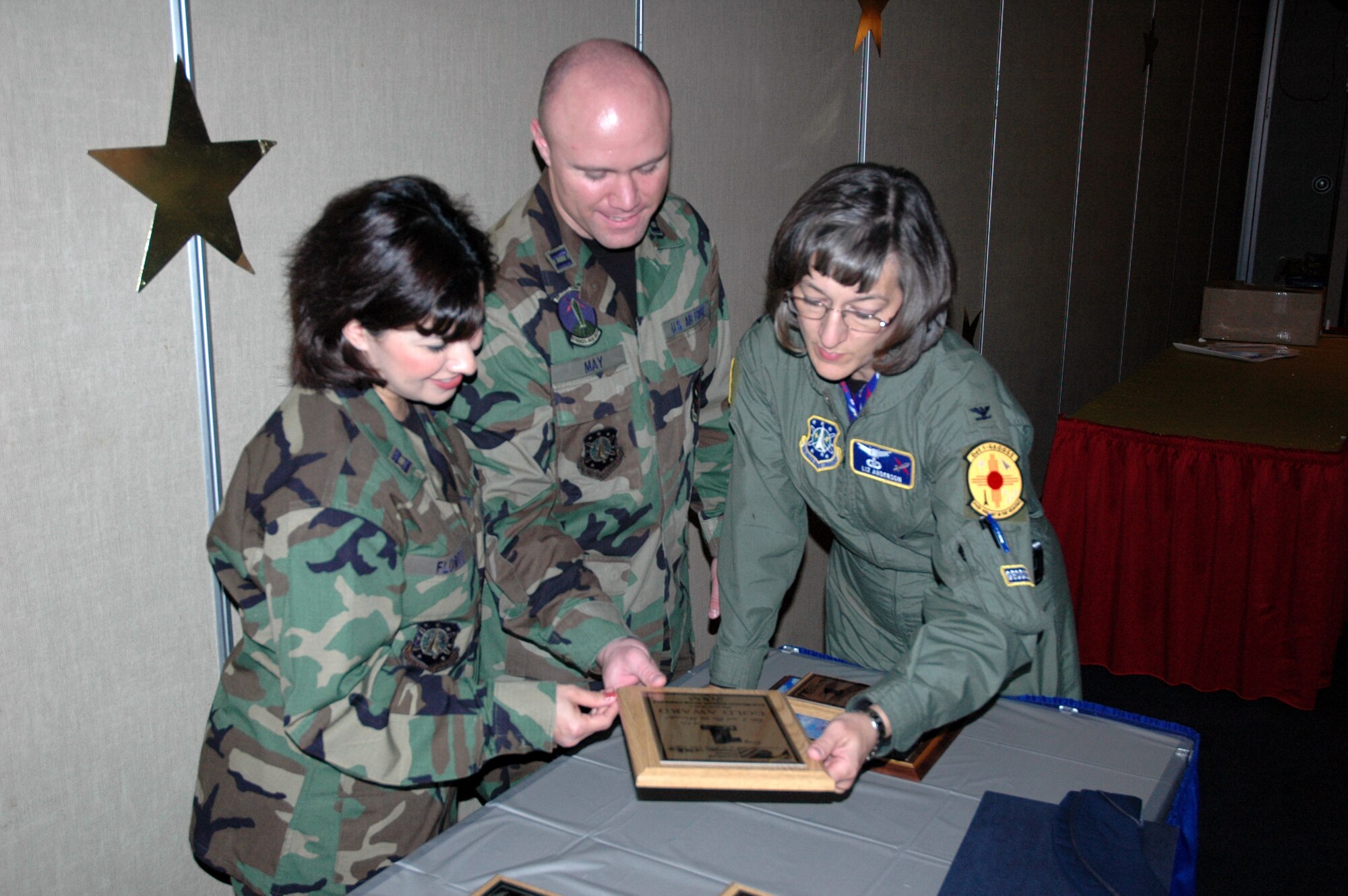 Col. Liz Anderson (right), individual mobilization augmentee to the 21st Space Wing commander, looks at the 21st Space Wing Silver Award at the CFC banquet Dec. 8 at the Officers Club. Capts. Jason May and Ida Flores (pictured) were the Combined Federal Campaign co-project officers for the installation. (U.S. Air Force photo by Steve Brady)