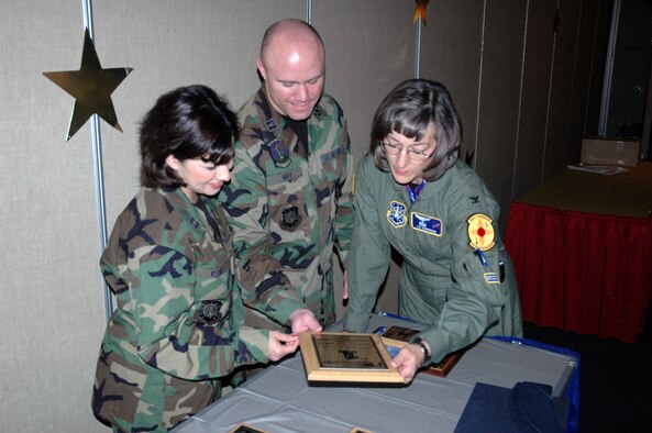 Col. Liz Anderson (right), individual mobilization augmentee to the 21st Space Wing commander, looks at the 21st Space Wing Silver Award at the CFC banquet Dec. 8 at the Officers Club. Capts. Jason May and Ida Flores (pictured) were the Combined Federal Campaign co-project officers for the installation. (U.S. Air Force photo by Steve Brady)